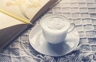 Home made cup of latte coffee beans and summer book on coffee table in work space with morning light or Cozy scene of relaxing in