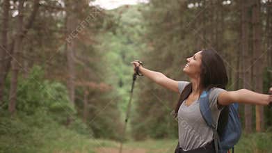 Young woman spreading arms and enjoying backpacking travel in the woods