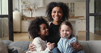 Happy mixed race family mother hugging diverse daughters at home
