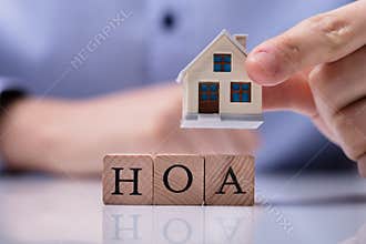 Businessman Placing House Models On HOA Cubic Blocks