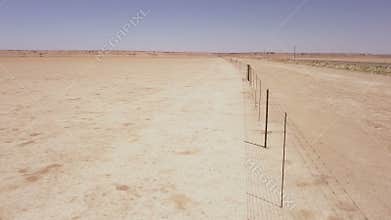 Aerial of a long fence running through a desert landscape