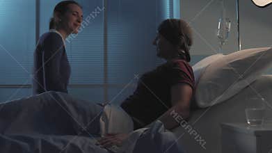 Caring woman hugging her friend with cancer at the hospital