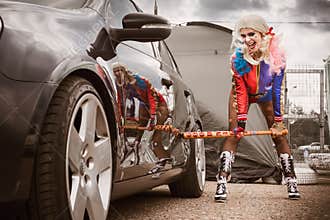 Moscow, Russia - July 06, 2020: Harley Quinn hits a parked black car with a baseball bat. There is a dent in the car, the car is