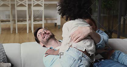 Happy dad playing with diverse ethnicity kids tickling at home