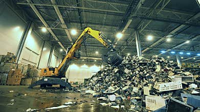 Indoors dumpsite with electronics debris and an excavator