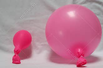 Two pink balloons on a white sheet