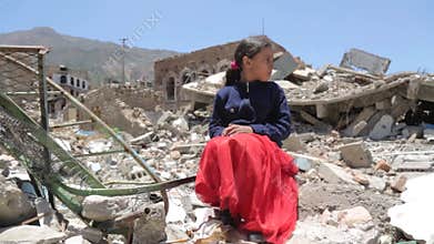 A sad Yemeni girl in front of rubble of destroyed homes