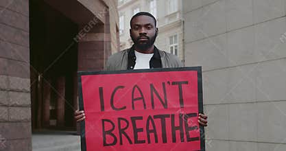 Young afro american guy holding placard with i cant breath writing. Male protestor supporting movement against police