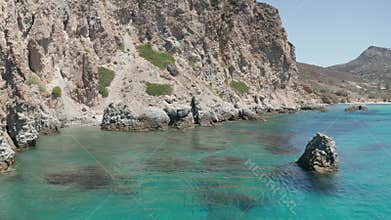 Slow Dolly Aerial in between rock fomations in Turquoise Blue Ocean Water on Greek Island Milos
