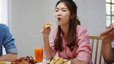 Happy young friends group having lunch at home. Asia family party eating pizza food and laughing enjoying meal while sitting at