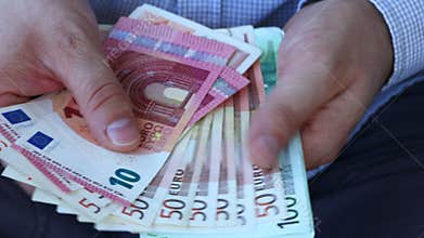 A man in a business shirt counting European money, Euro. Various banknotes
