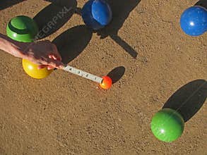 A ruler in inches measures the outcome of a game of bocce.