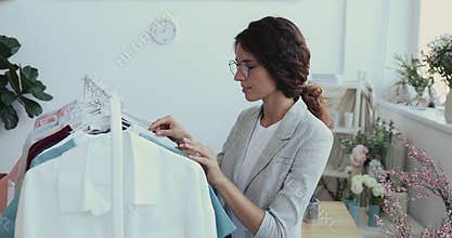 Young businesswoman choosing new collection female clothes.