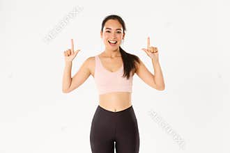 Sport, wellbeing and active lifestyle concept. Smiling energized asian fitness girl, female athlete inviting for event