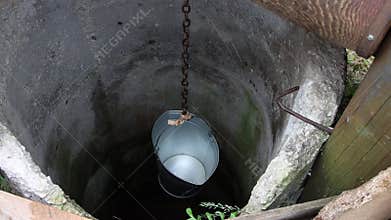 An empty bucket slowly sinks into the well.