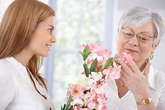 Pretty woman greeting mother with flowers smiling