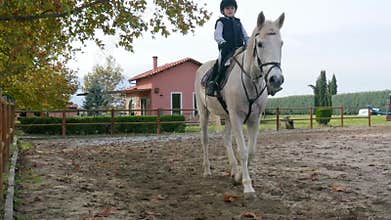 Child riding a horse on a ranch.