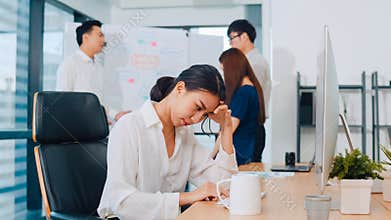 Millennial young Chinese businesswoman working stress out with project research problem on computer desktop in meeting room at