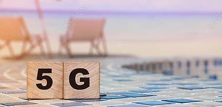 5G letters on wood blocks on swimming pool borders and beach. Big data concept