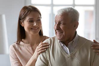 Young woman cuddling shoulders of joyful elderly mature 70s father.