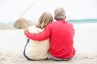 Senior Couple On Holiday Sitting On Winter Beach