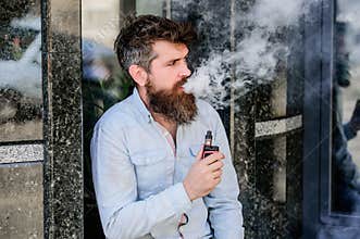 Habits concept. man smoking e-cigarette. hipster man hold vaping device. Mature hipster with beard. Health safety and