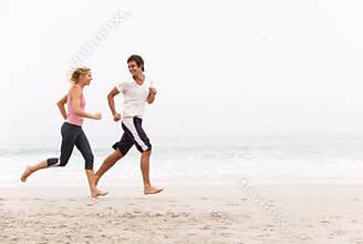 Young Couple Running Along Winter Beach