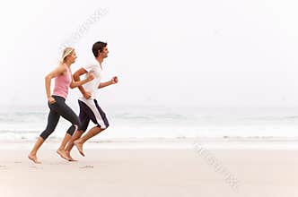 Young Couple Running Along Winter Beach