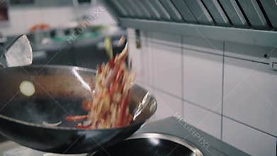 Chef fries food in a wok pan