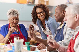 Group Of Retired Seniors Attending Art Class In Community Centre With Teacher