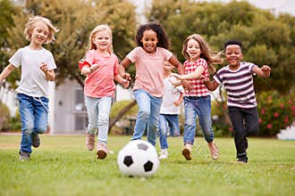 Group Of Children Playing Football With Friends In Park