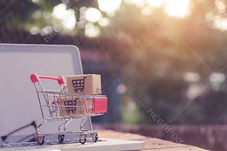 Shopping online concept - Parcel or Paper cartons with a shopping cart logo in a trolley on a laptop keyboard. Shopping service on