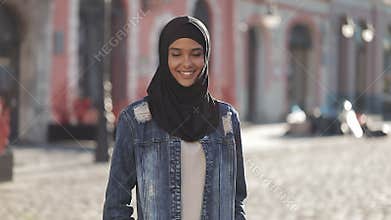 Portrait of beautiful young Muslim woman wearing hijab headscarf smiling into the camera standing on the old city