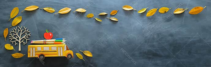 Back to school concept. Top view banner of cardboard school bus, apple and pencil next to tree with autumn dry leaves over