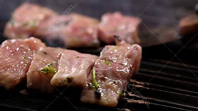 Chef moving pieces of marinated surgeons with metallic spatula on hot surface of barbecue grill