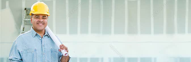 Hispanic Male Contractor Wearing Hard Hat Against Drywall Banner Background with Ladder