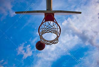 A Basketball going into a Basketball Hoop