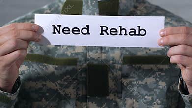 Need rehab written on paper in hands of male soldier, help to war veterans