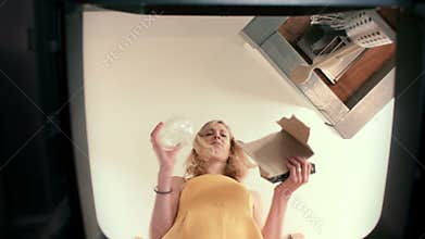 Trash Can Point of View of a Young Woman hesitating when between Paper and Plastic when recycling