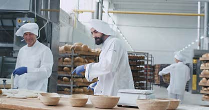Bakery factory enthusiastic dancing baker chef while preparing the dough for baking the bread dancing and listening