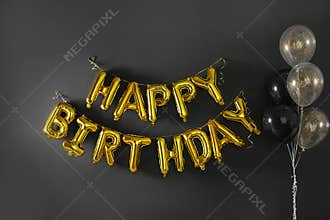 Phrase HAPPY BIRTHDAY made of golden balloon letters on black