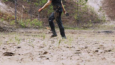 A man in a dirty race is walking in a muddy puddle.