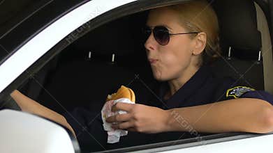 Lady cop eating burger in patrol car, unhealthy snack, digestion problems risk