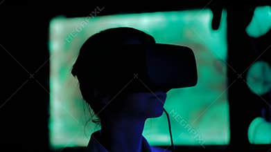 Young woman using virtual reality headset at dark interactive exhibition
