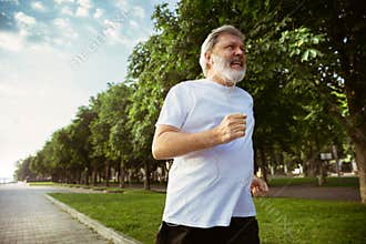 Senior man as runner with armband or fitness tracker at the city`s street