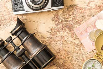 Travel accessories binoculars, compass on old, antique Europe map