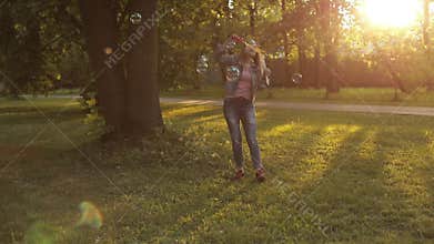 Group of happy little children girl playing trying catch big air soap bubble blower