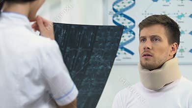 Happy man in foam cervical collar on doctors appointment, positive x-ray result