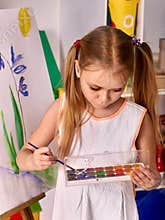 Kid girl paint on an easel