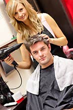 Happy hairdresser drying her customer's hair